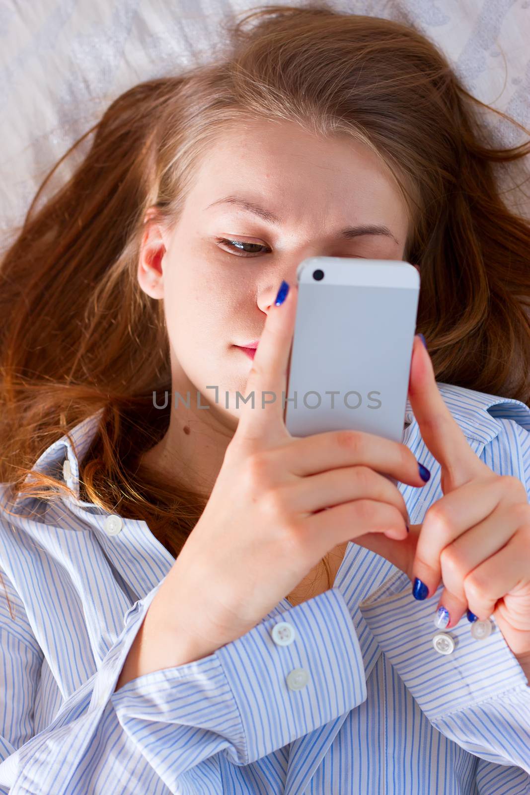 Beautiful woman sending a text with a mobile phone in bed