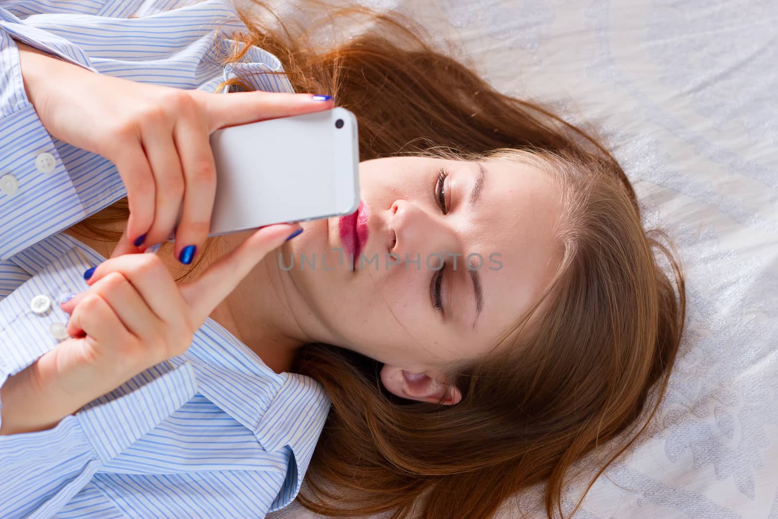 Beautiful woman sending a text with a mobile phone in bed