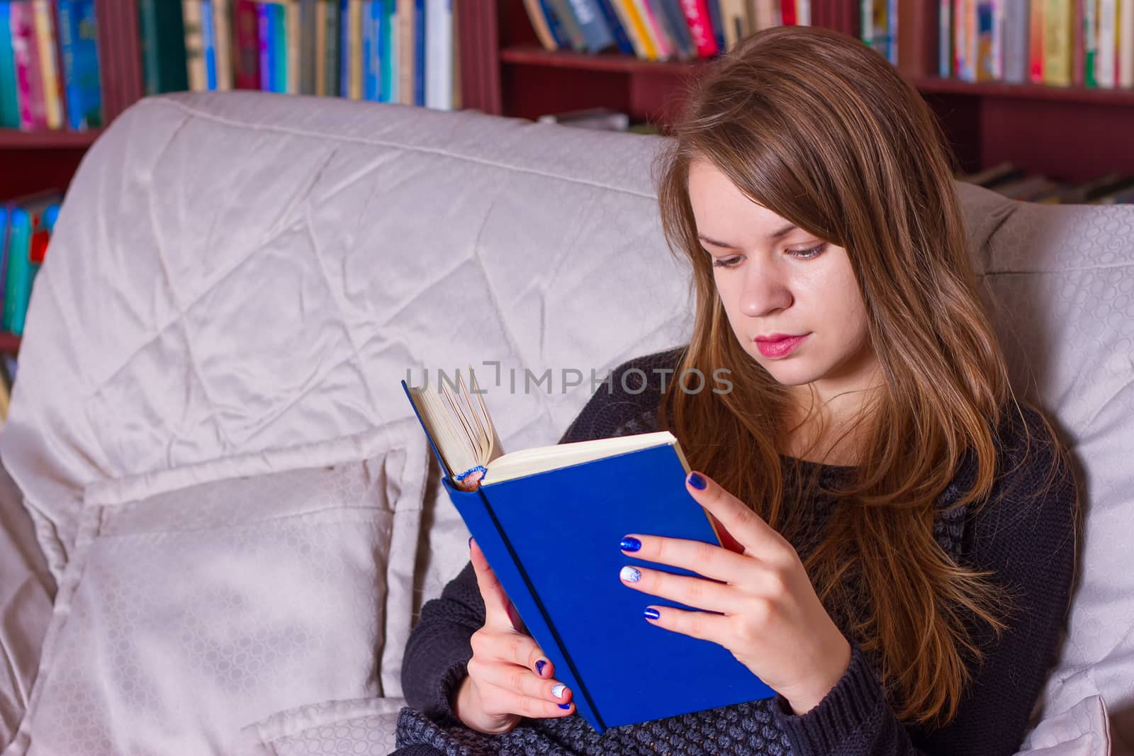 A girl reading a book on the couch