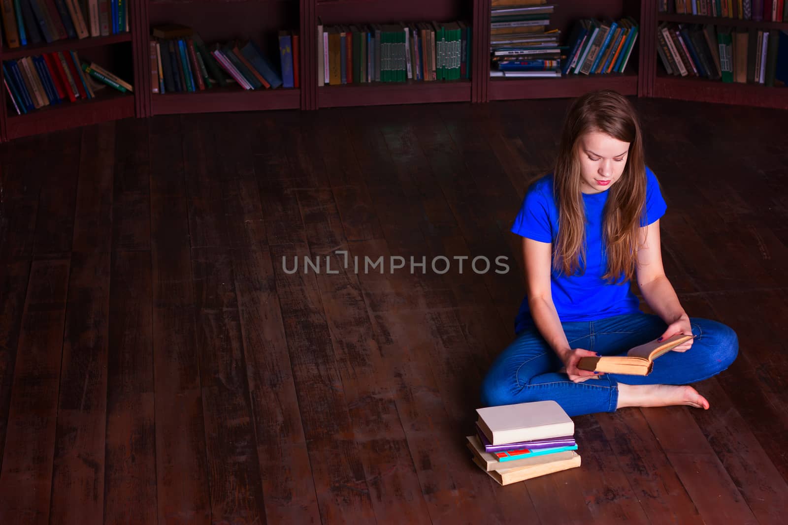 A girl sits on the floor in the library