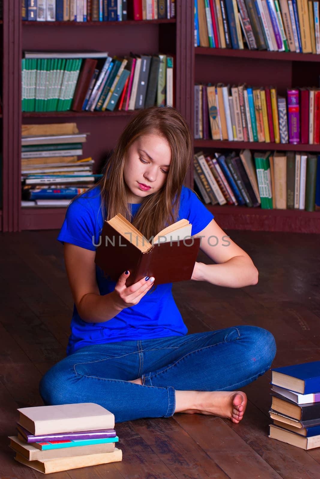 A girl sits on the floor in the library