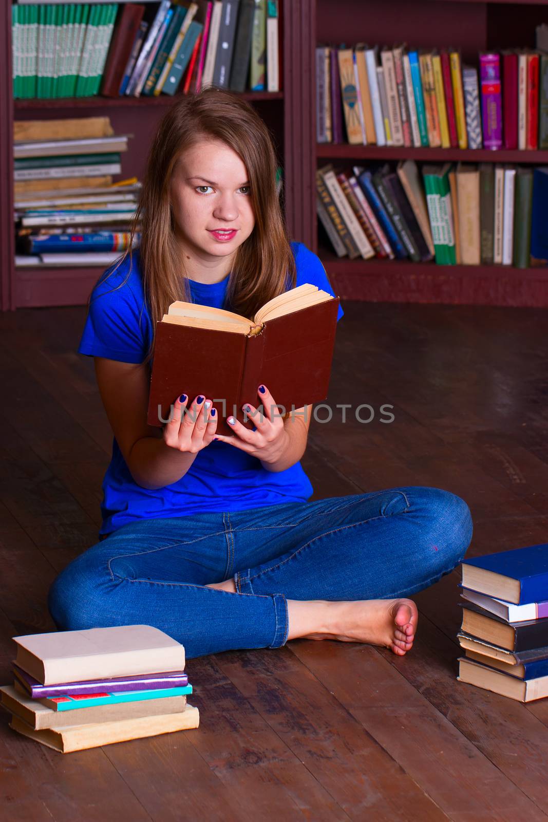 A girl sits on the floor in the library