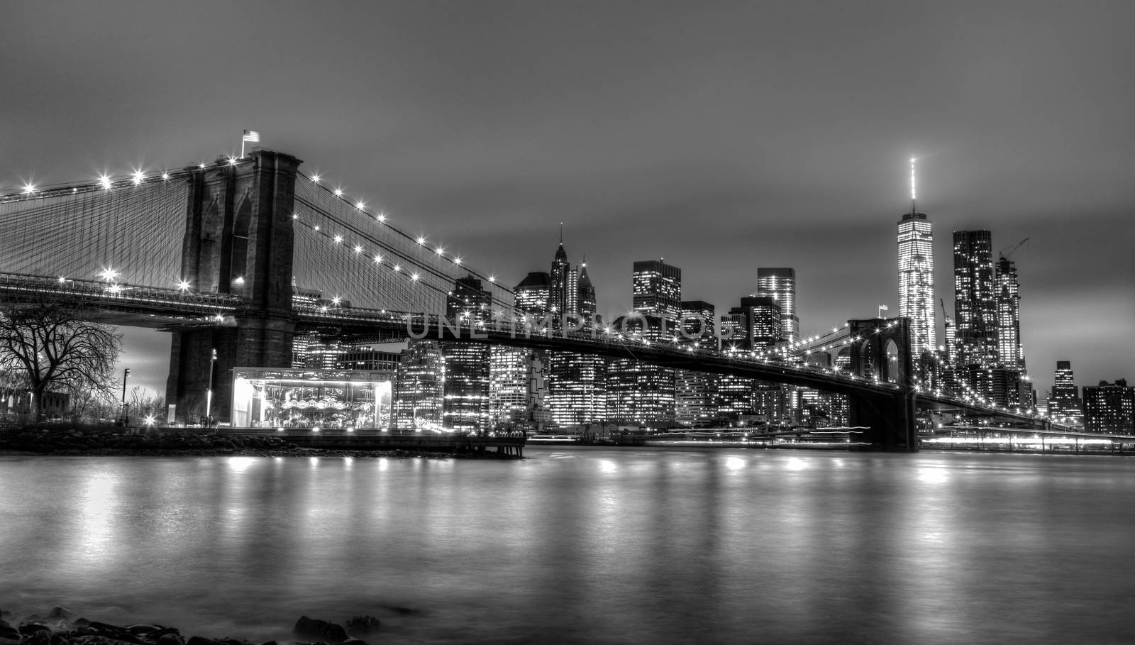 Brooklyn bridge and New York City Manhattan downtown skyline at dusk with skyscrapers illuminated over East River panorama. Copy space. Black and white image.