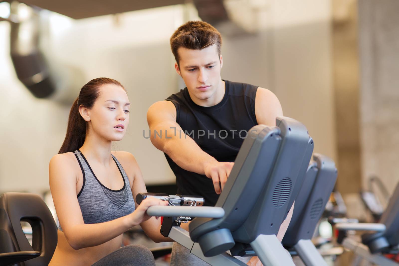 woman with trainer on exercise bike in gym by dolgachov