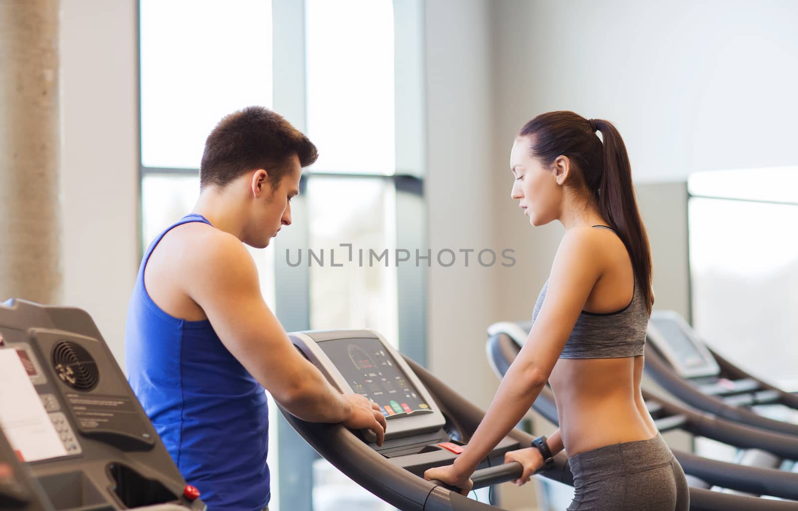 woman with trainer on treadmill in gym by dolgachov