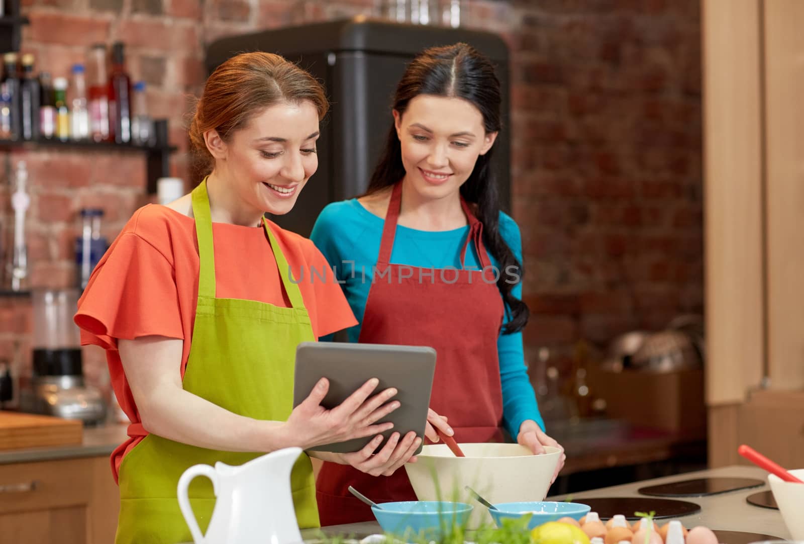 happy women with tablet pc cooking in kitchen by dolgachov