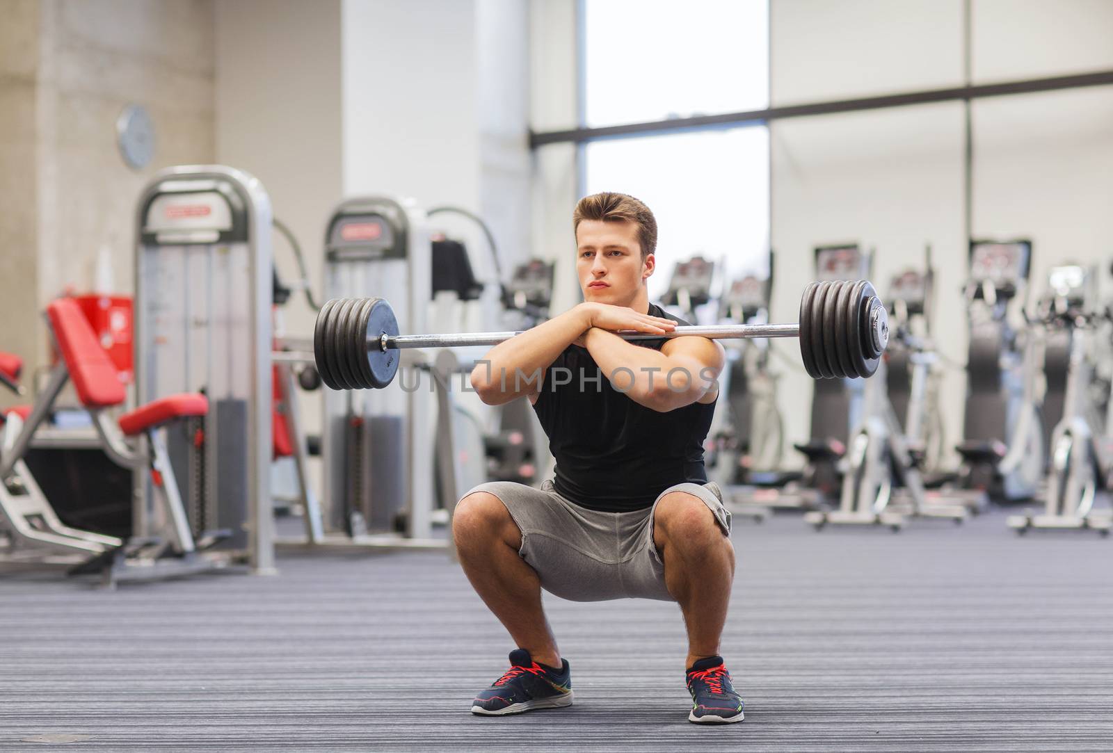 sport, bodybuilding, lifestyle and people concept - young man with barbell doing squats in gym