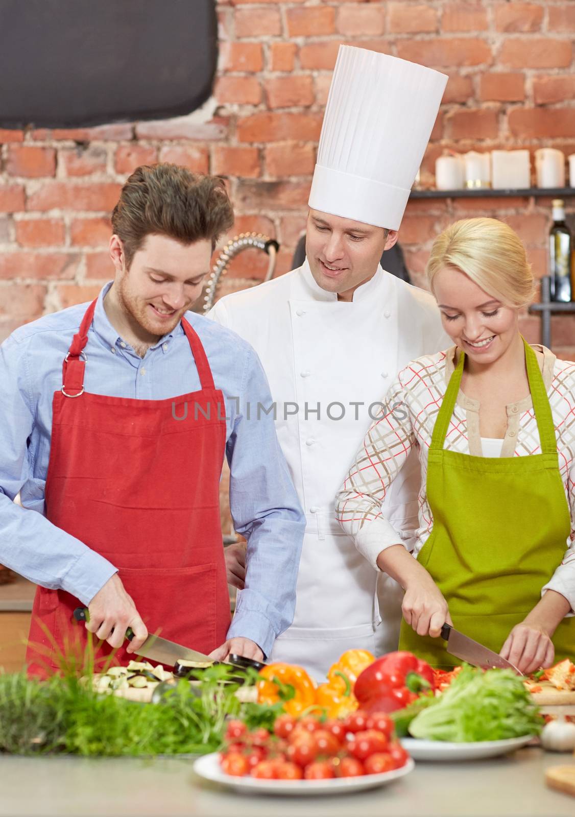 cooking class, culinary, food and people concept - happy couple and male chef cook cooking in kitchen