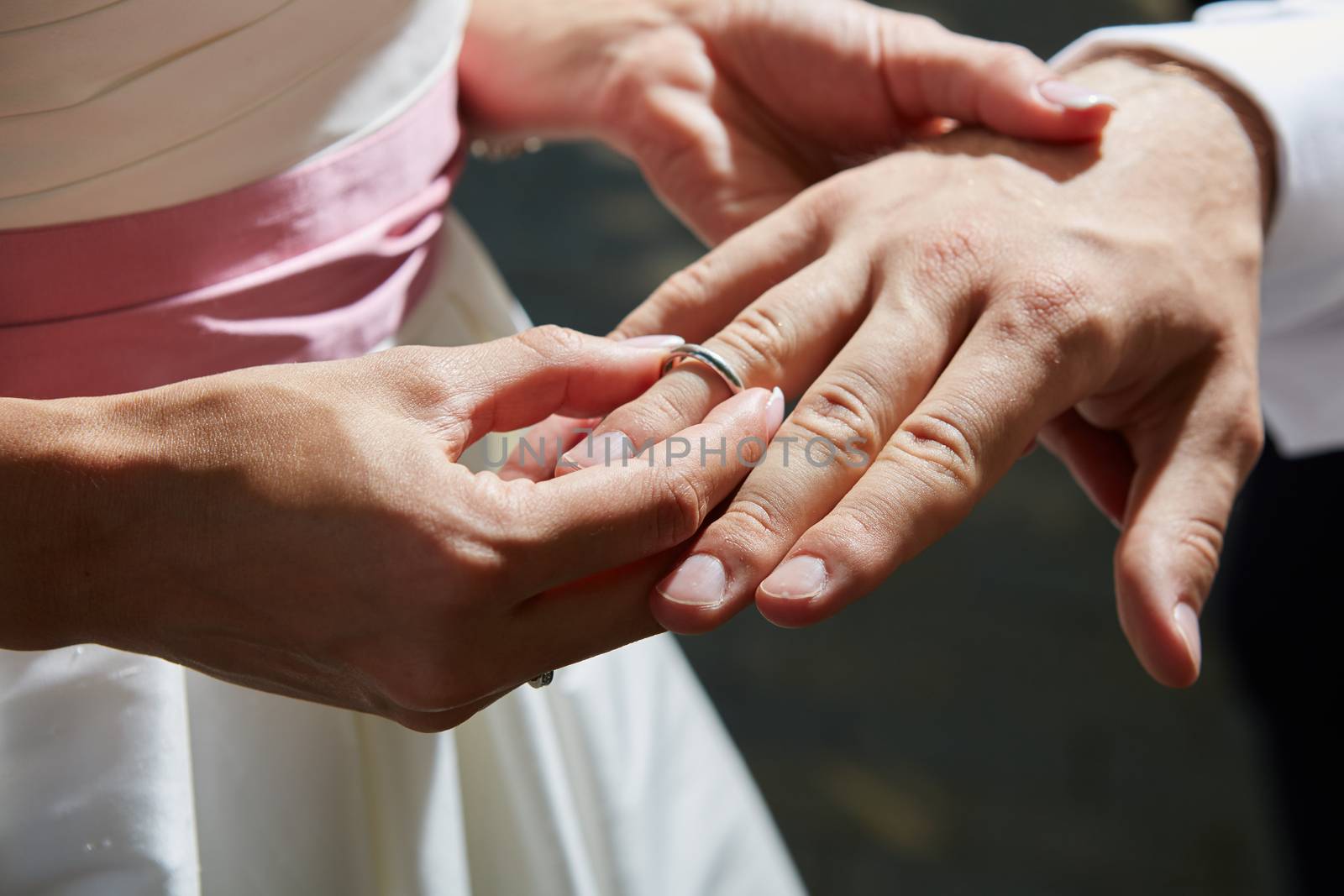 bride puts ring on the finger of groom