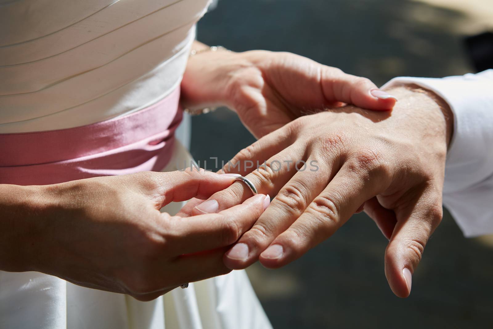 bride puts ring on the finger of groom