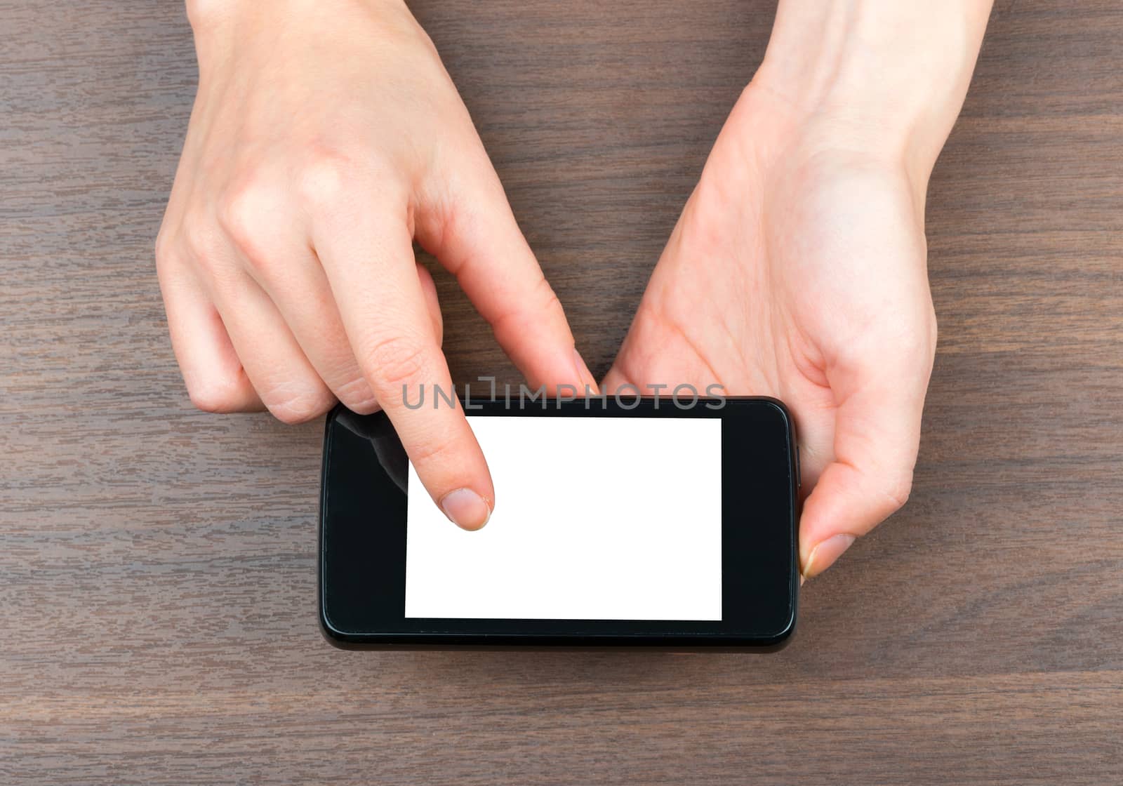 Humans hands holding smartphone on wooden table