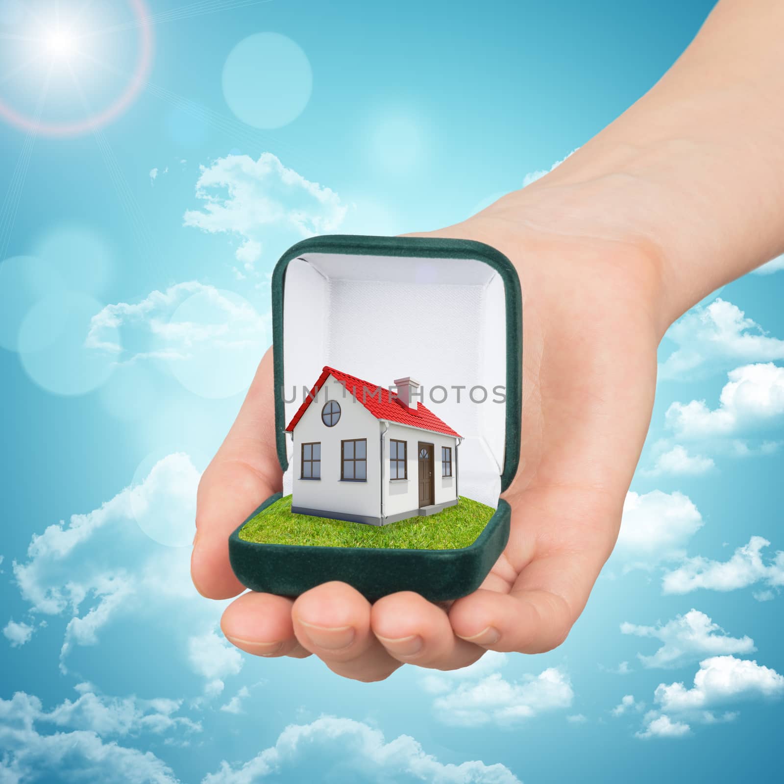 Empty ring box house in humans hand on blue sky background