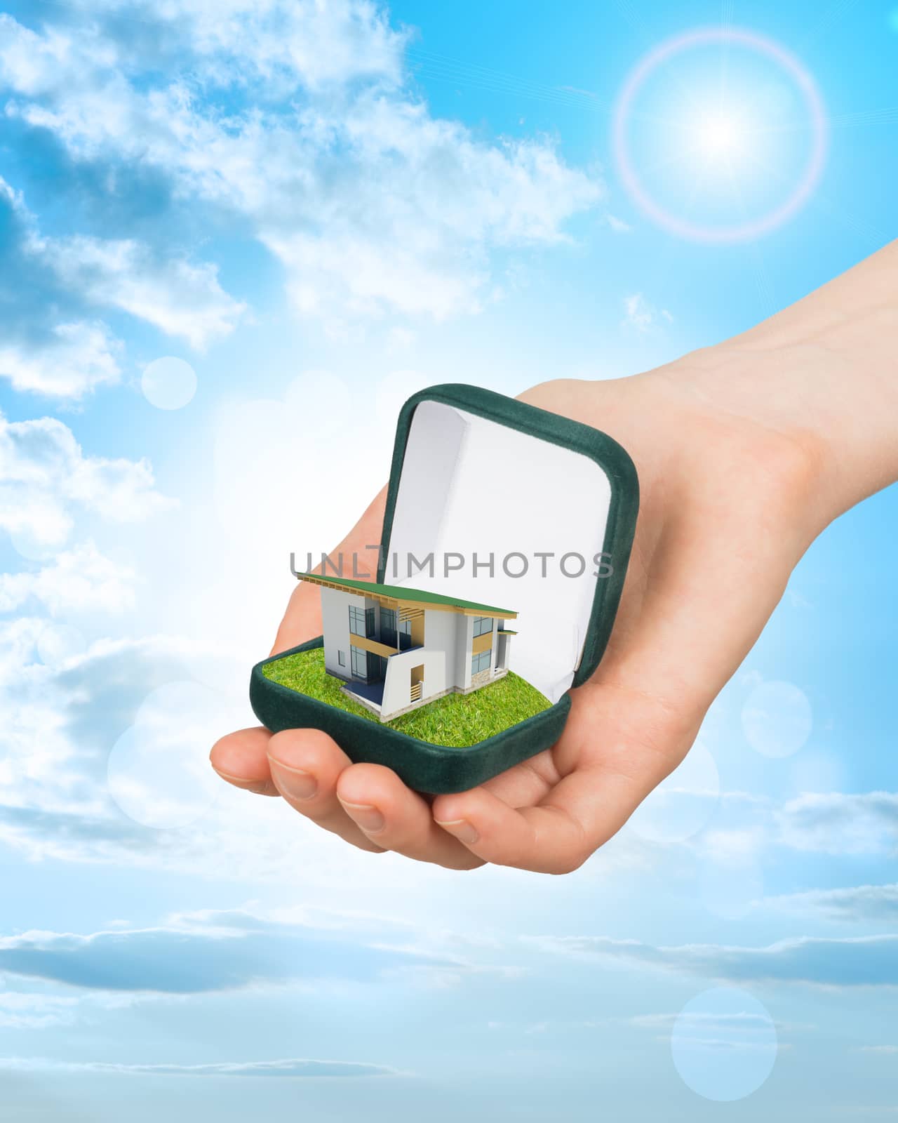 Empty ring box house in humans hand on blue sky background