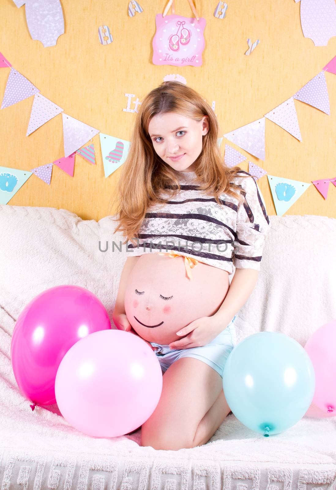 Pregnant woman with painted eyes on his stomach and mouth