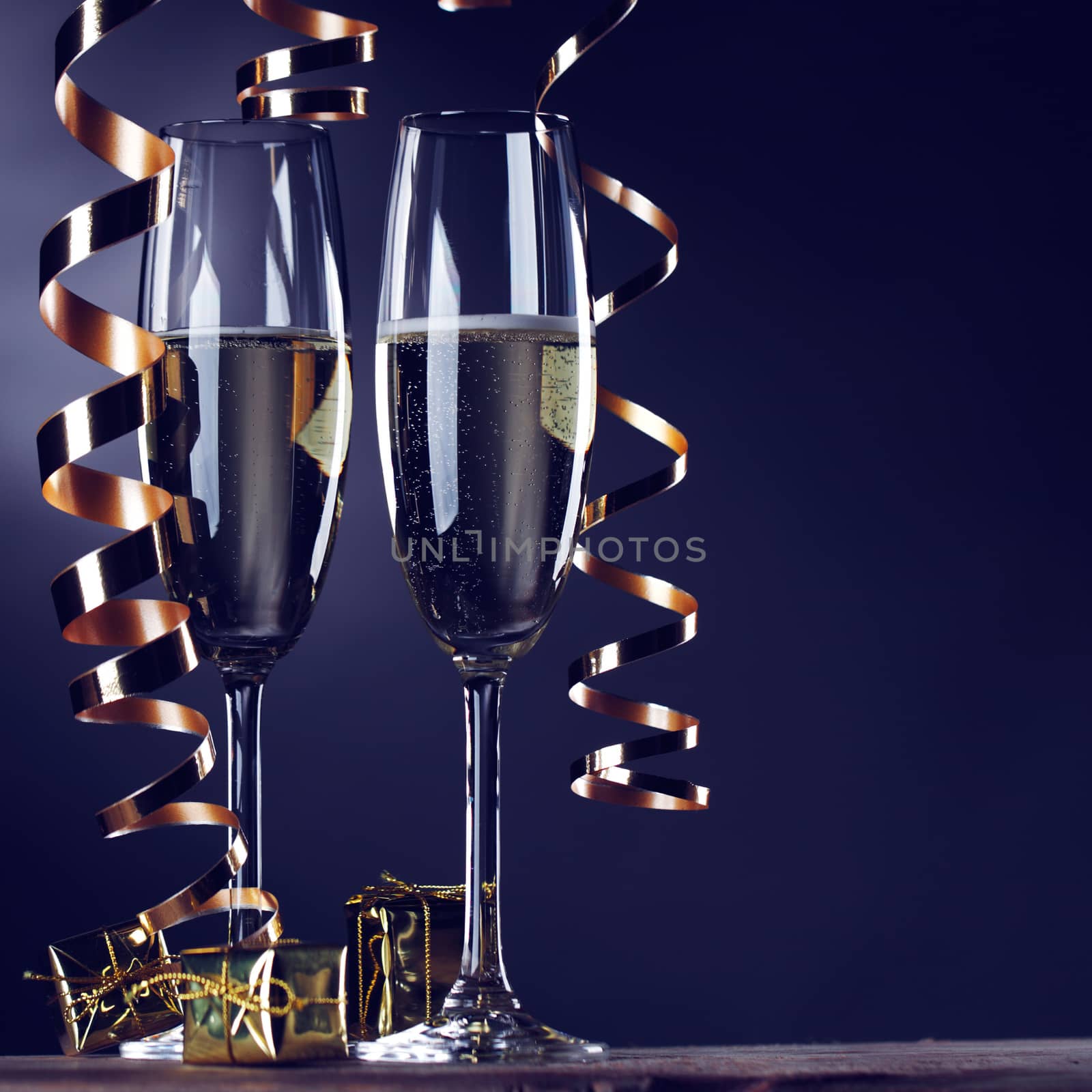 Two champagne glasses and curly ribbons on dark background