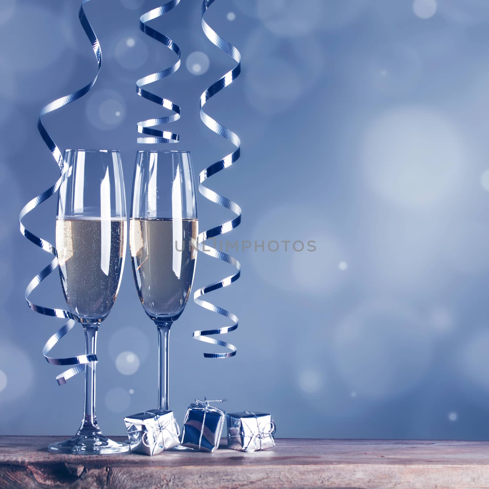 Two champagne glasses and curly ribbons on dark background