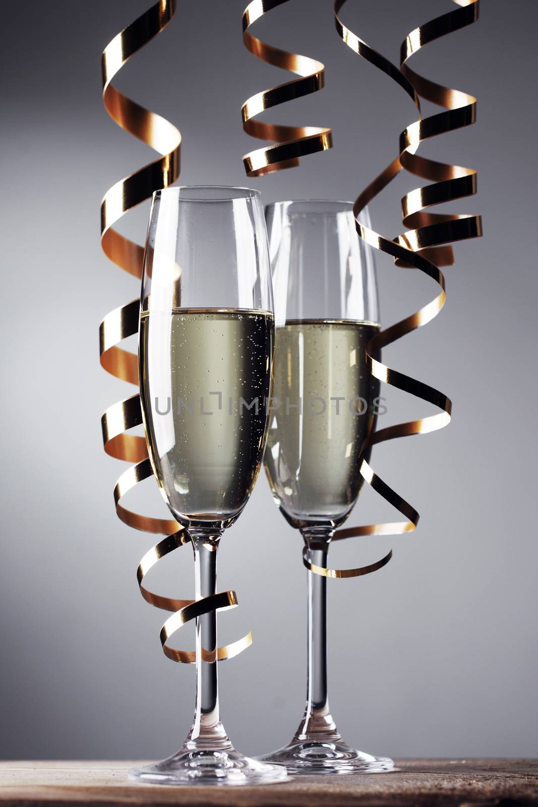 Two glasses of champagne and ribbons on light bokeh background