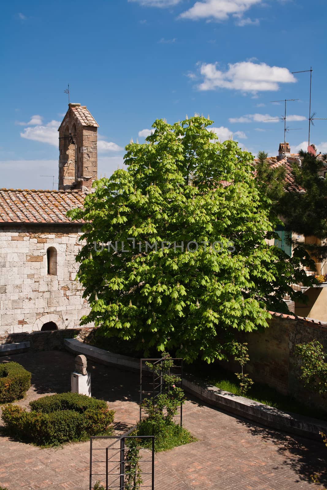 An old stone roman church and a garden in San Quirico d'Orcia in Italy
