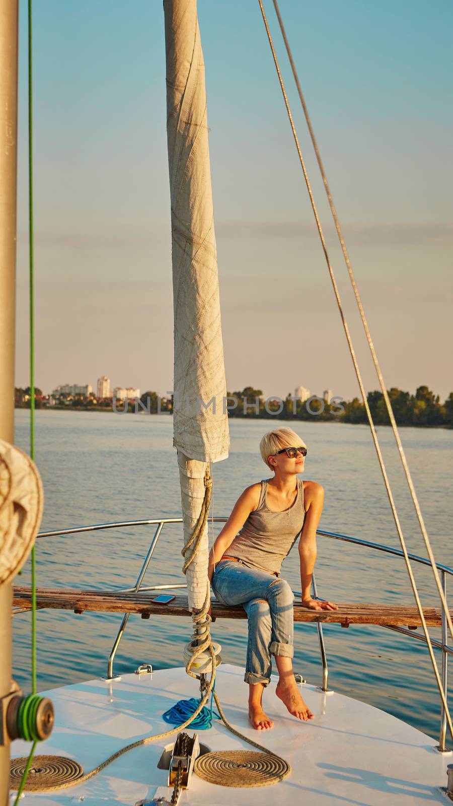 Woman traveling by boat at sunset by sarymsakov