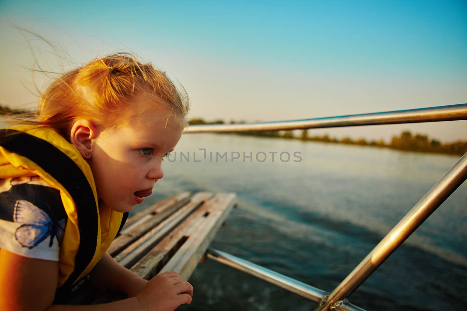 Little girl enjoying ride on yacht at sunset