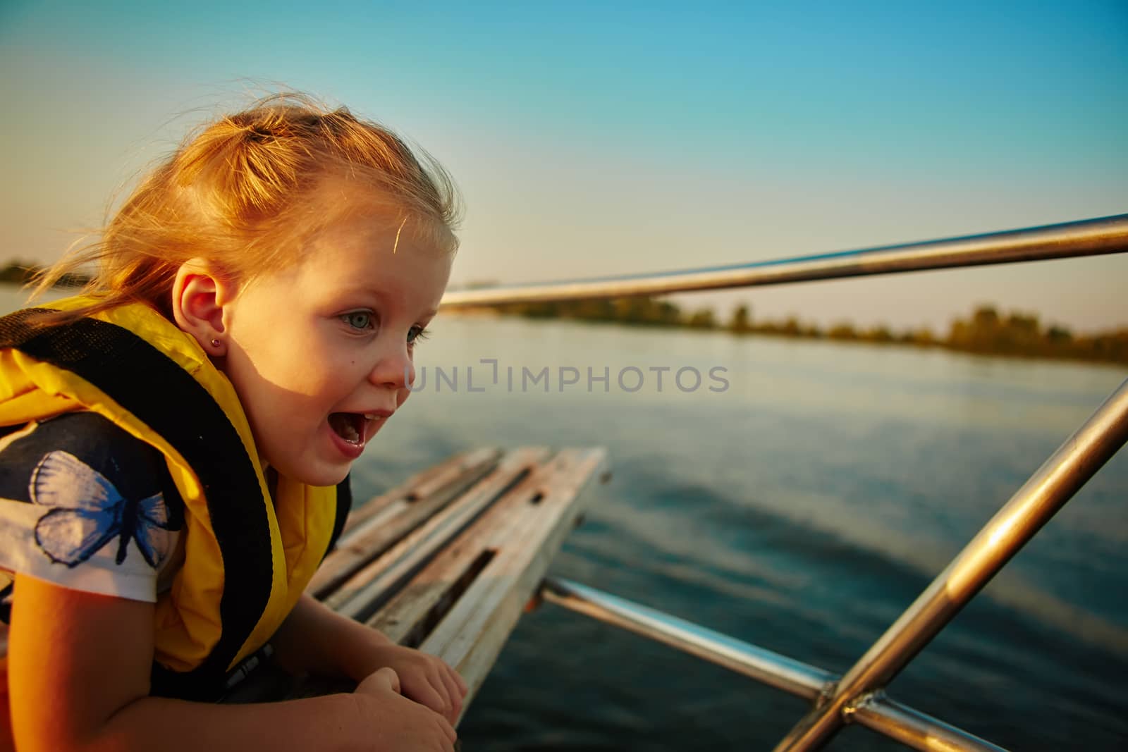 Little girl enjoying ride on yacht at sunset