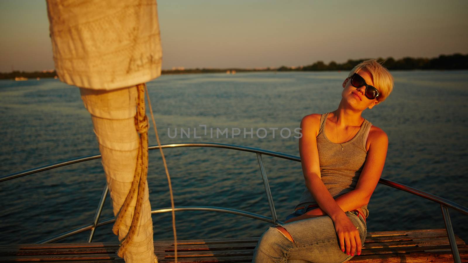 Woman traveling by boat at sunset by sarymsakov