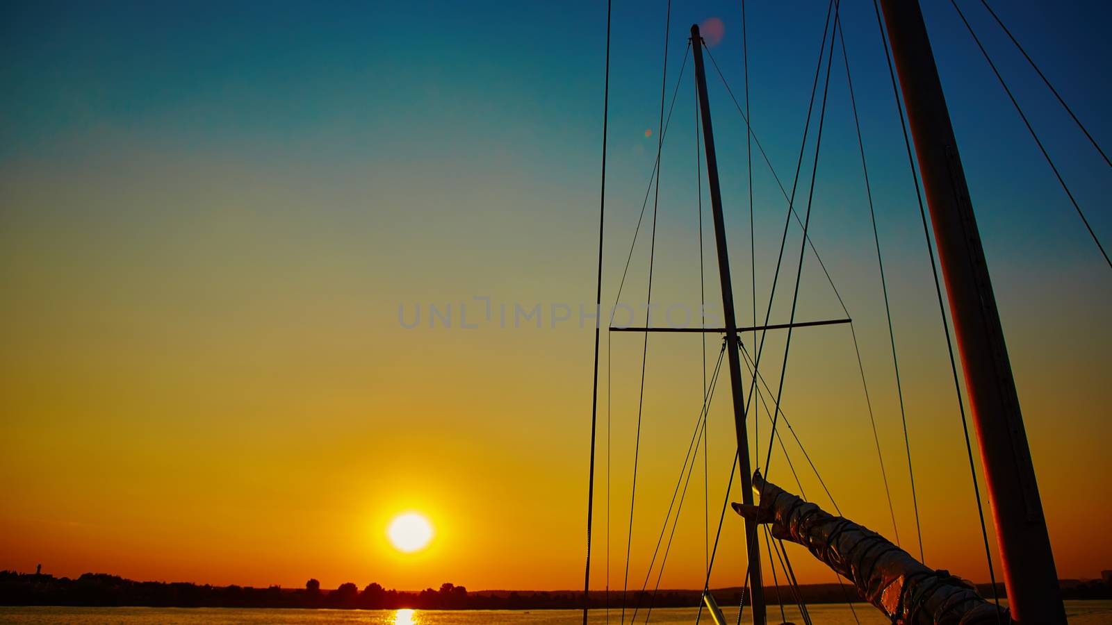 Sail boat gliding in sea at sunset by sarymsakov