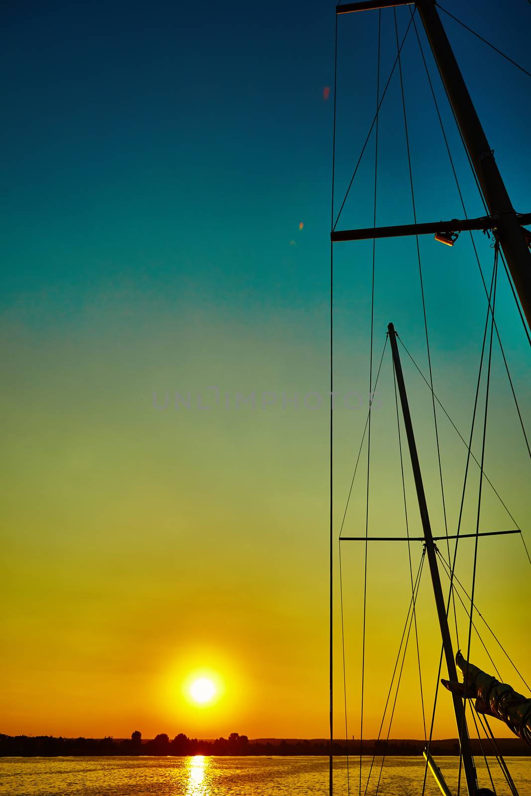 Sail boat gliding in sea at sunset by sarymsakov