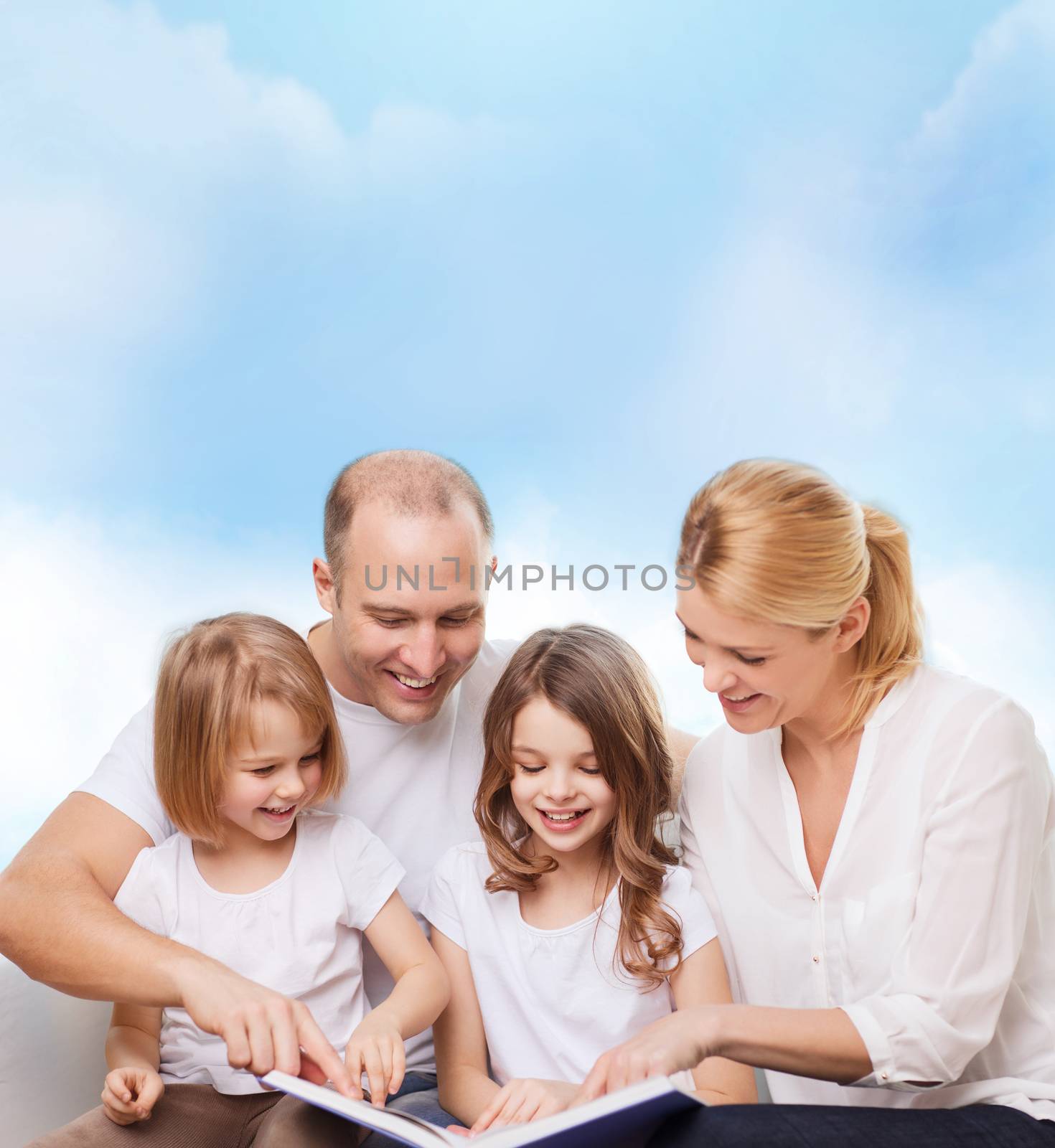 family, childhood, dream and people - smiling mother, father and little girls reading book over blue sky background