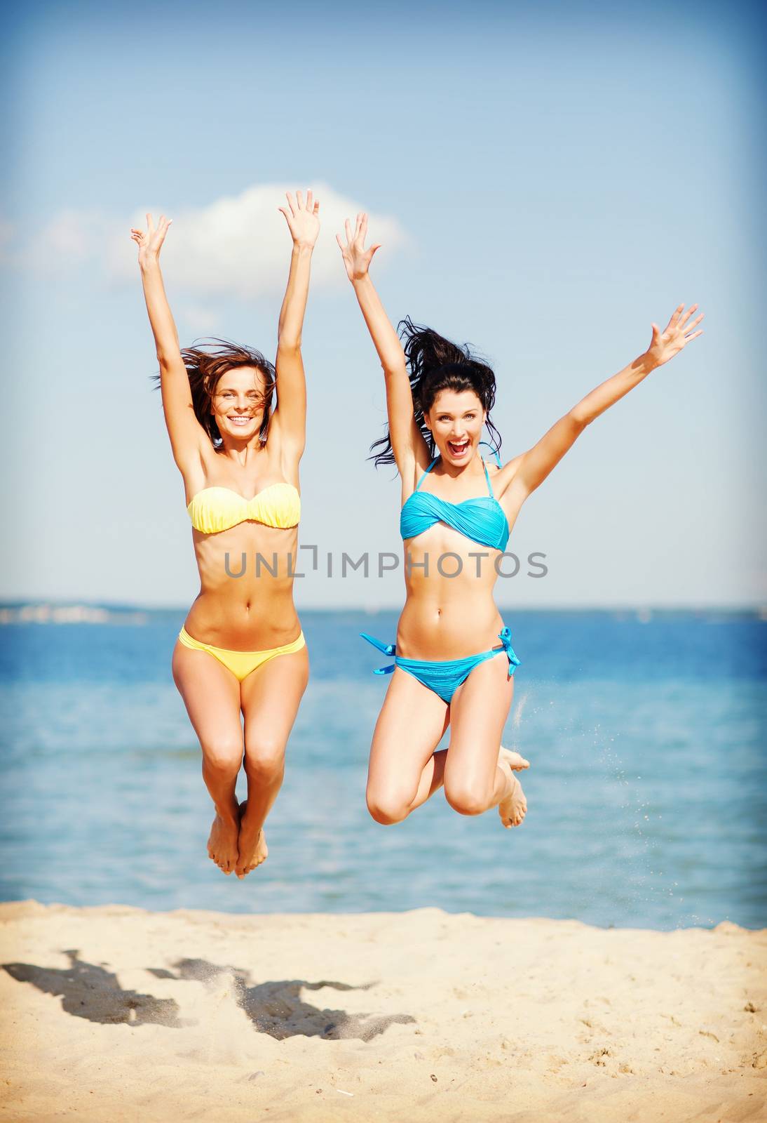 summer holidays and vacation - girls jumping on the beach