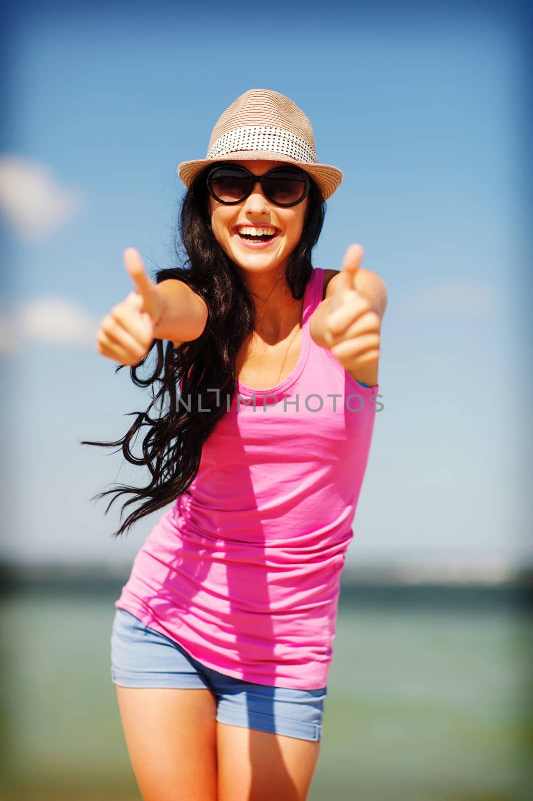 summer holidays and vacation - girl showing thumbs up on the beach