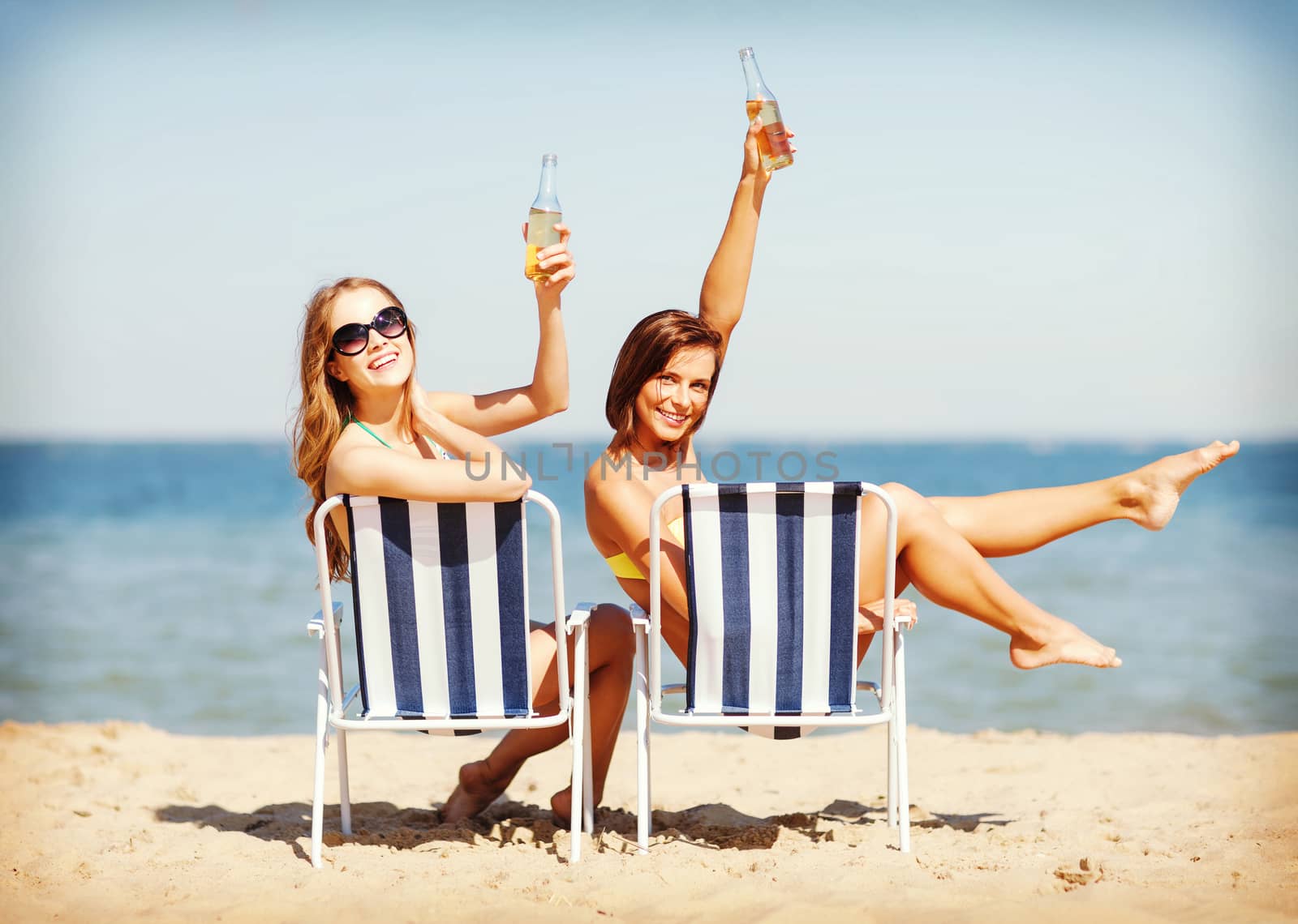summer holidays and vacation - girls sunbathing and drinking on the beach chairs