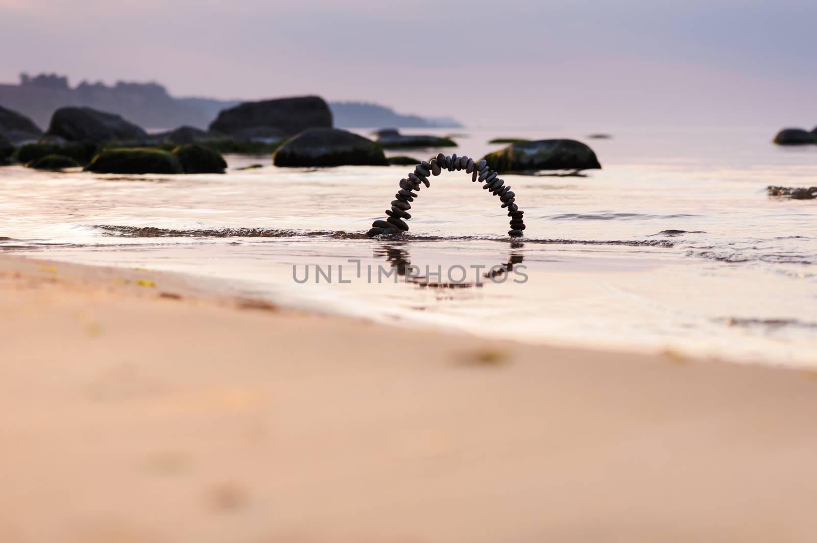 Arch of pebbles on the sandy beach of the sea