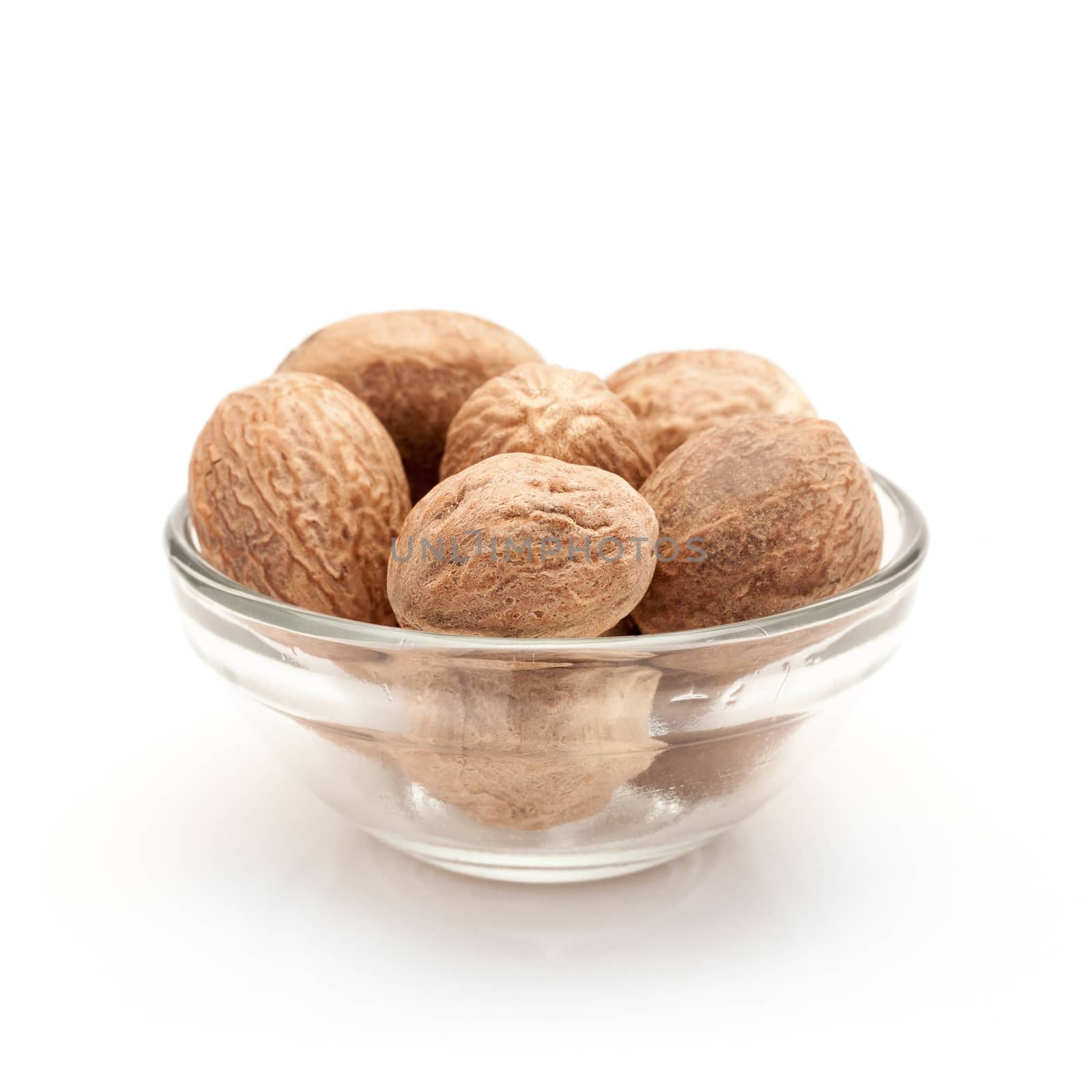 Front view of Organic Nutmeg Seed or Jaiphal (Myristica fragrans) in glass bowl isolated on white background.