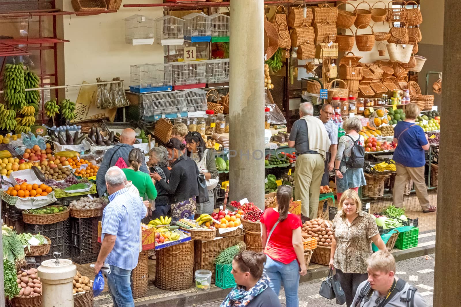 Funchal, Portugal - June 3, 2013: Market in Funchal, Madeira. Exterior view from the patio - different booth with merchants trading fruits, baskets and flowers with tourists and locals.
