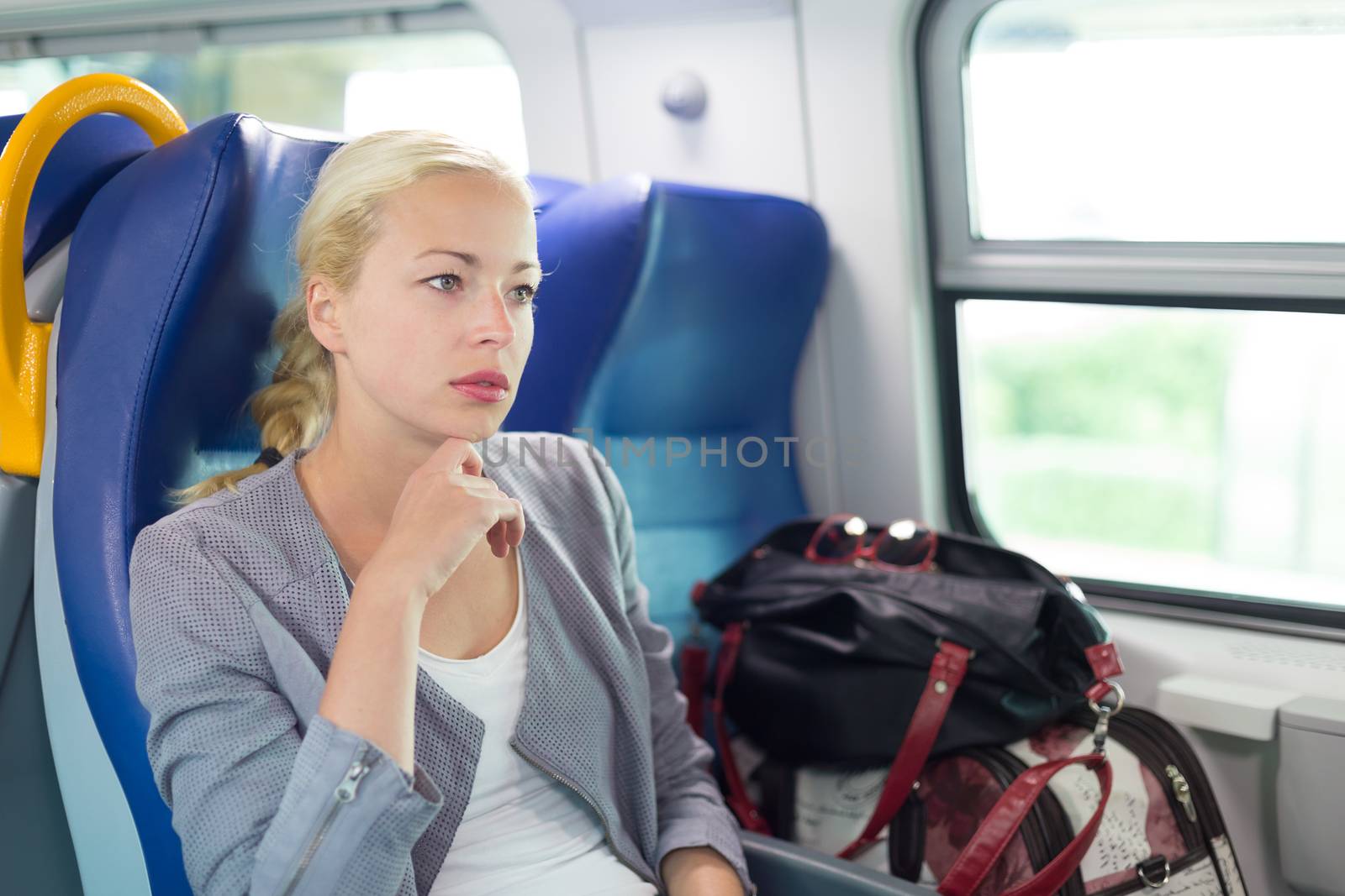 Blonde caucasian business woman traveling by train. Business travel concept.