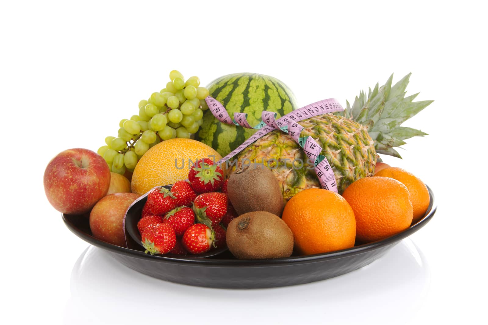 Big plate with lots of healthy fruits andmeasure tape over white background