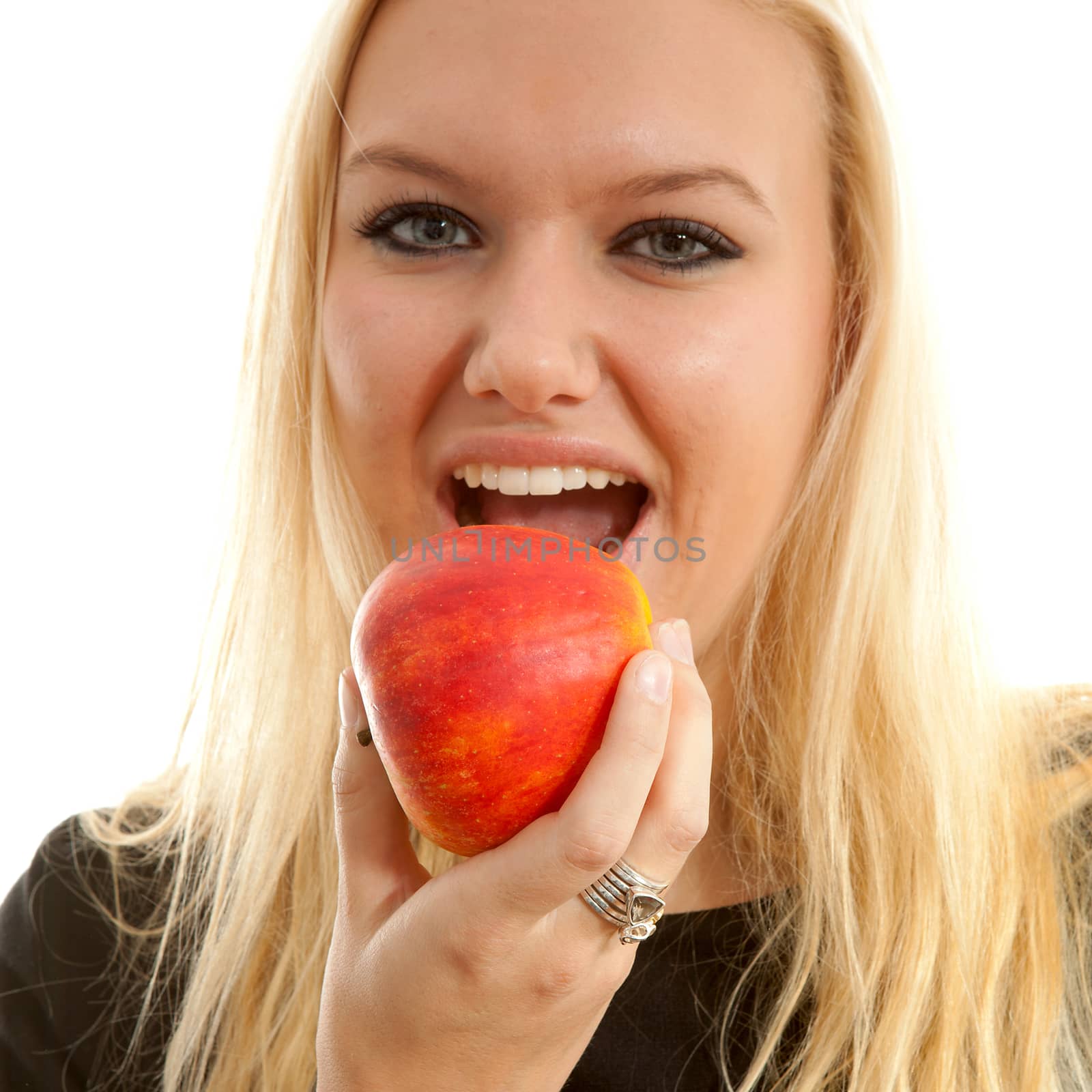 healthy lifestyle: portrait of young blonde woman eating delicious apple over white background