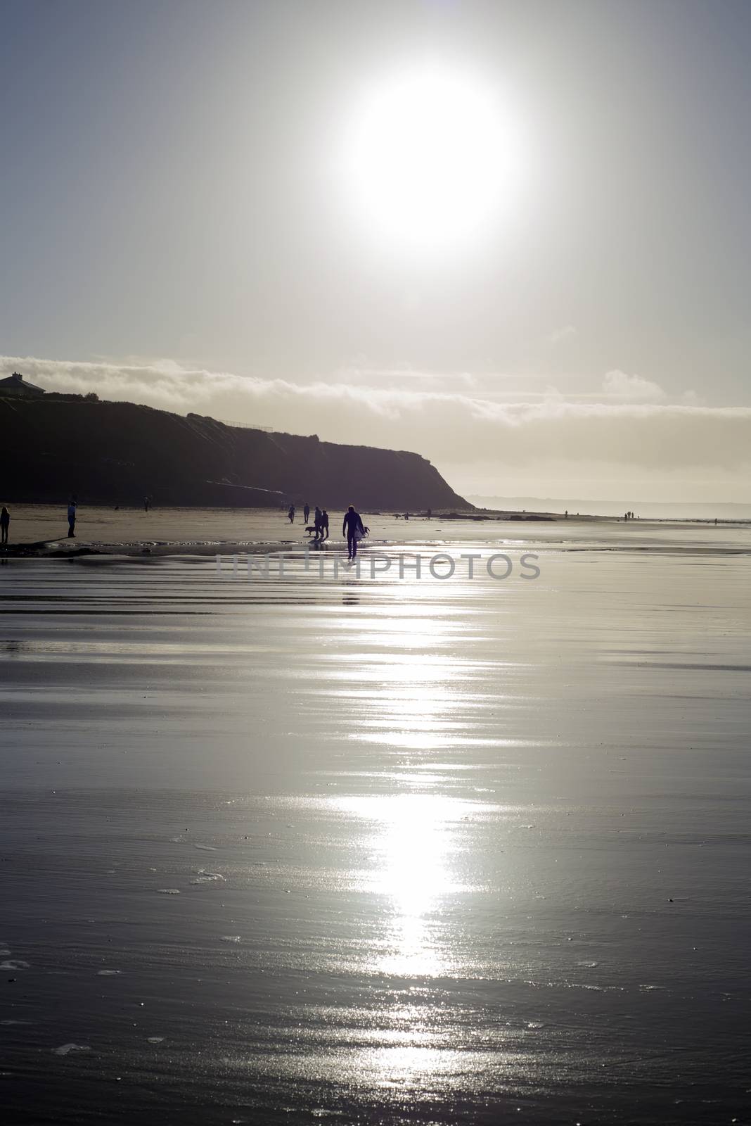 silhouette of surfer and people out for a walk as the sun sets in Ballybunion county Kerry Ireland