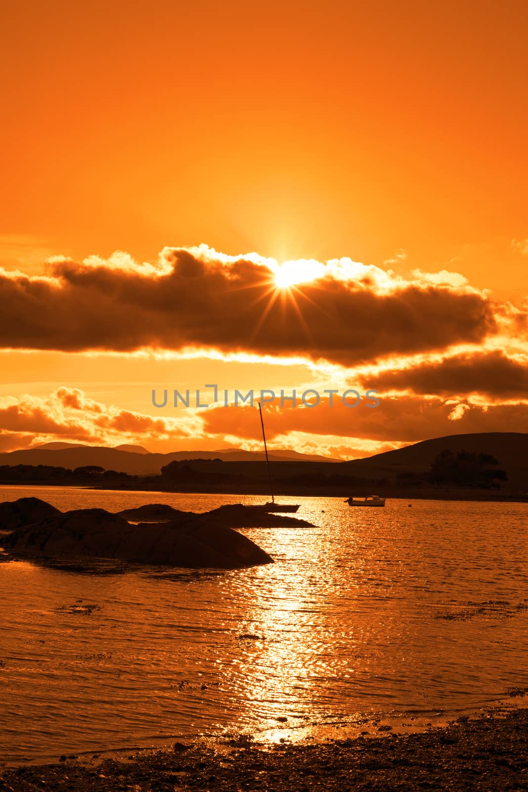 boats in a quiet bay near kenmare on the wild atlantic way ireland with an orange sunset