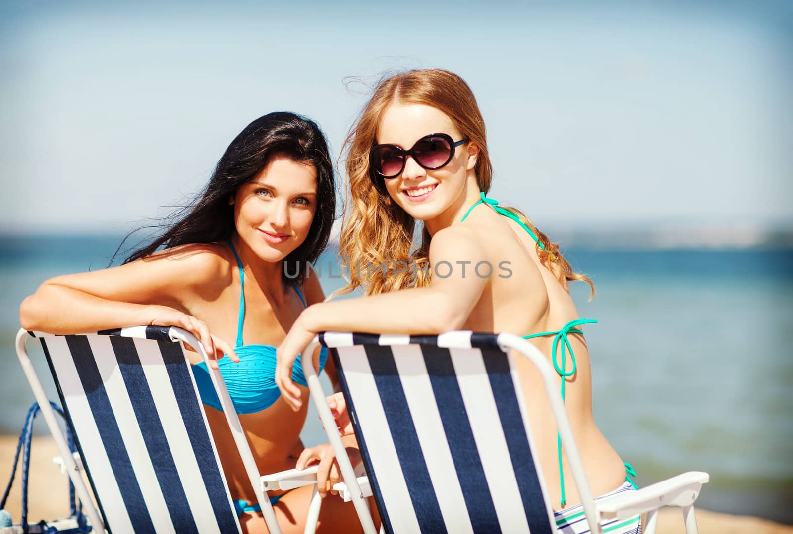 girls sunbathing on the beach chairs by dolgachov