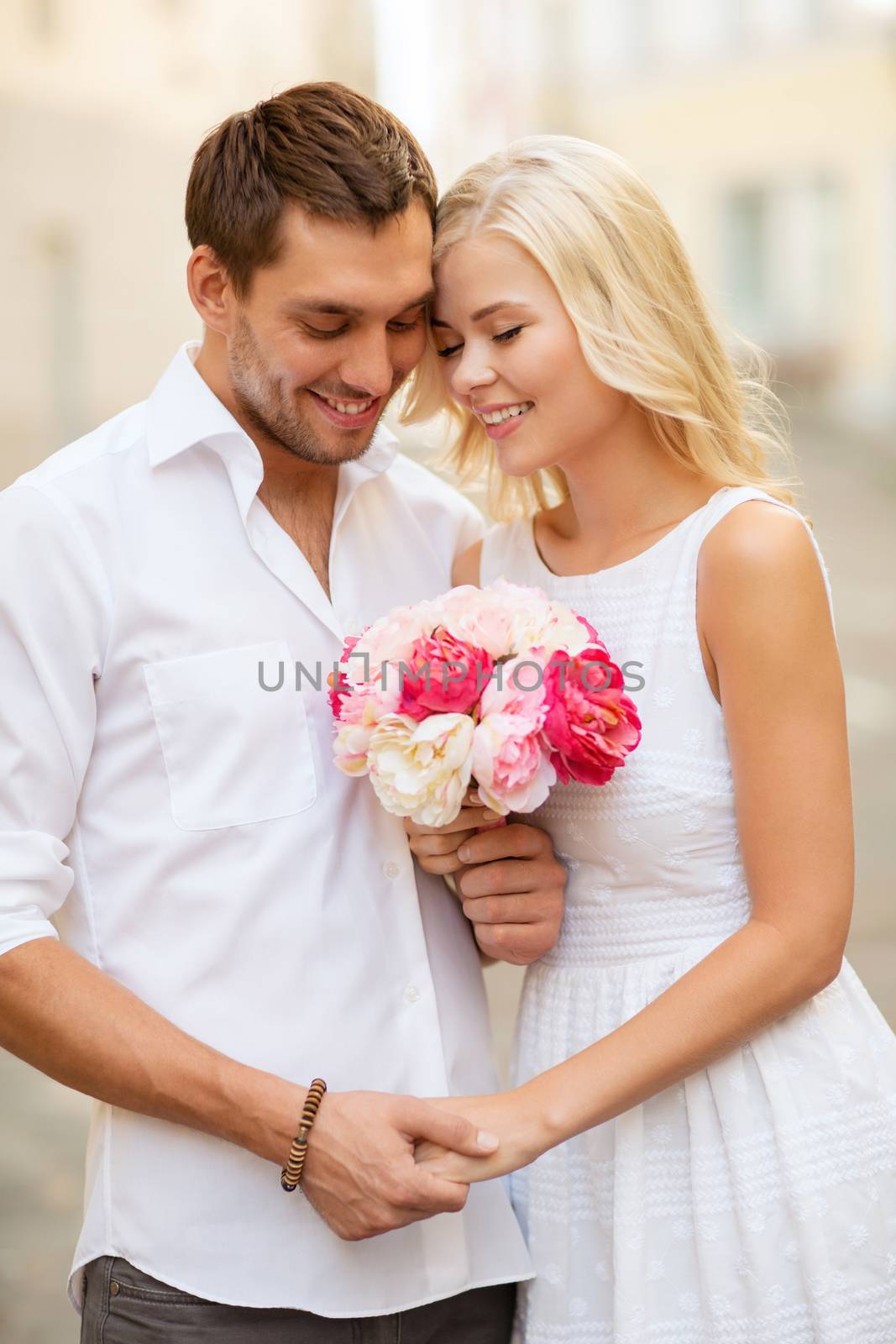 summer holidays and dating concept - couple with bouquet of flowers in the city