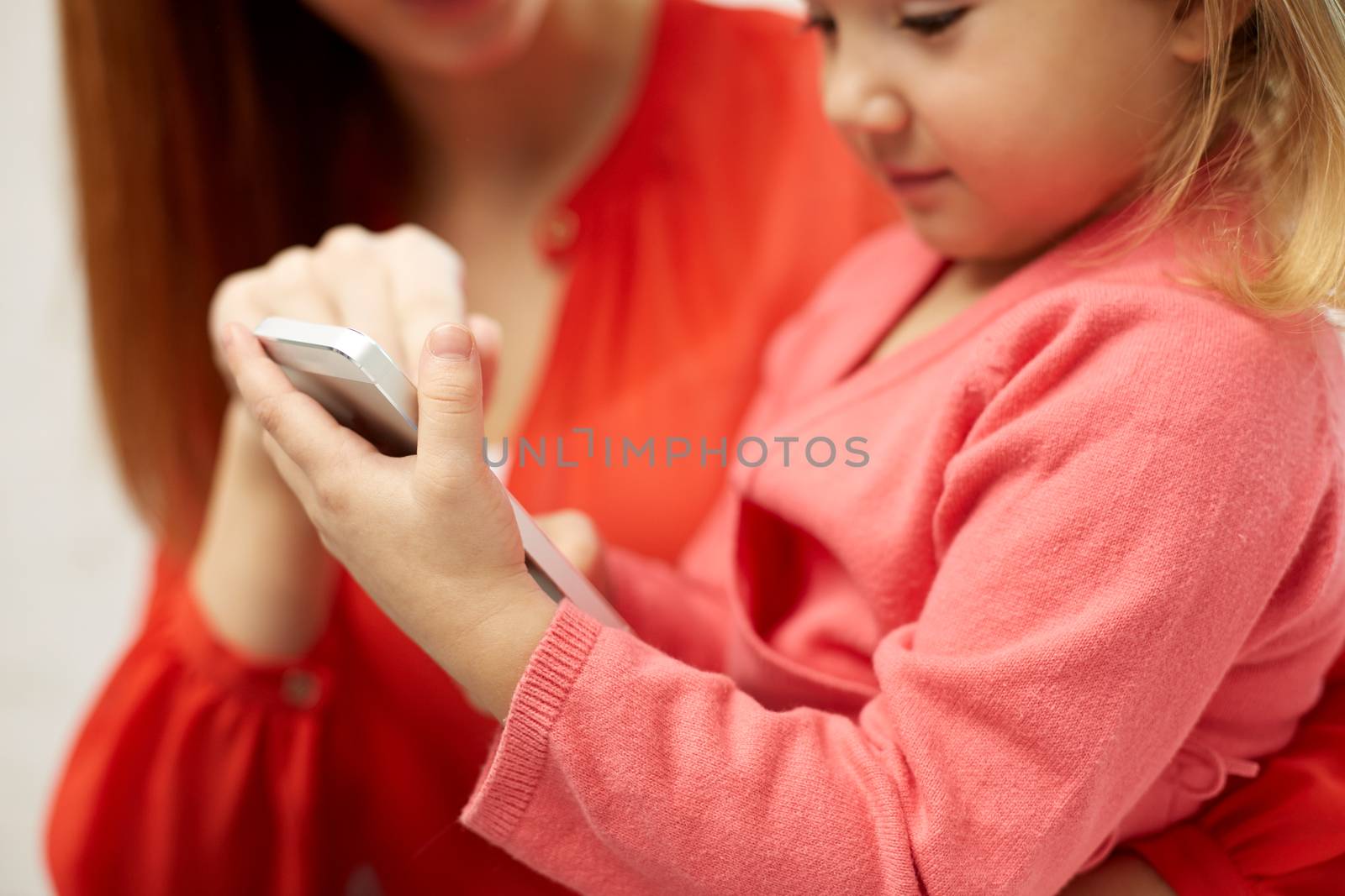 close up of woman and little girl with smartphone by dolgachov