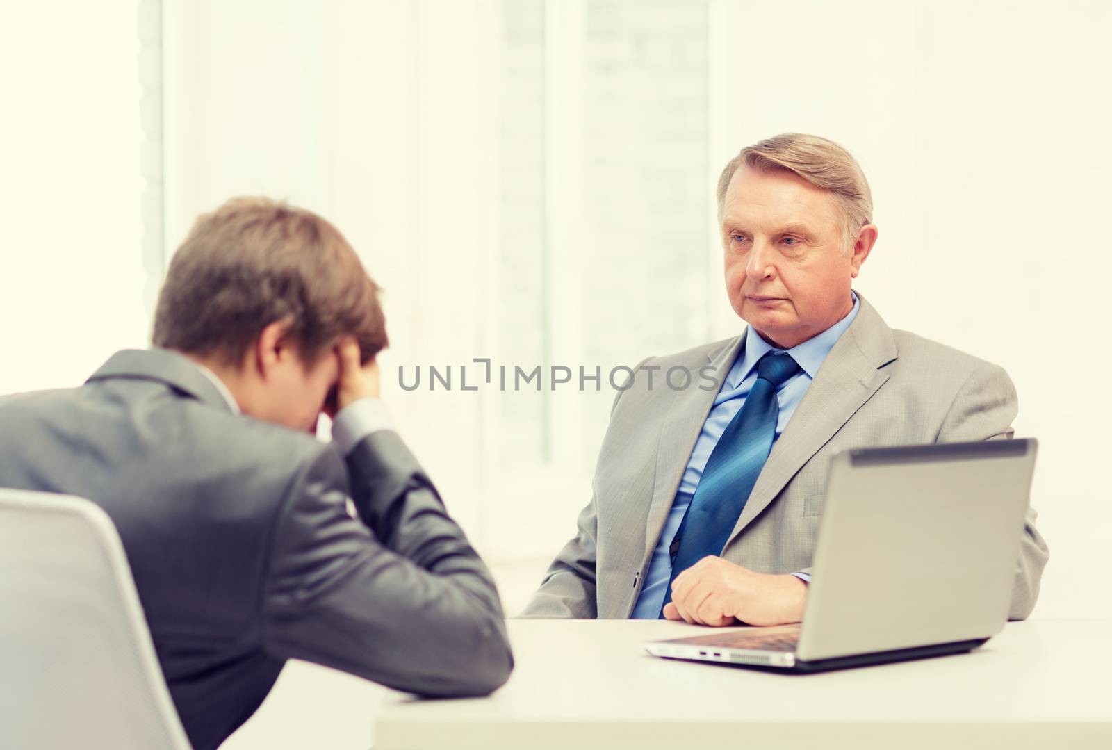 business, technology and office concept - older man and young man having argument in office