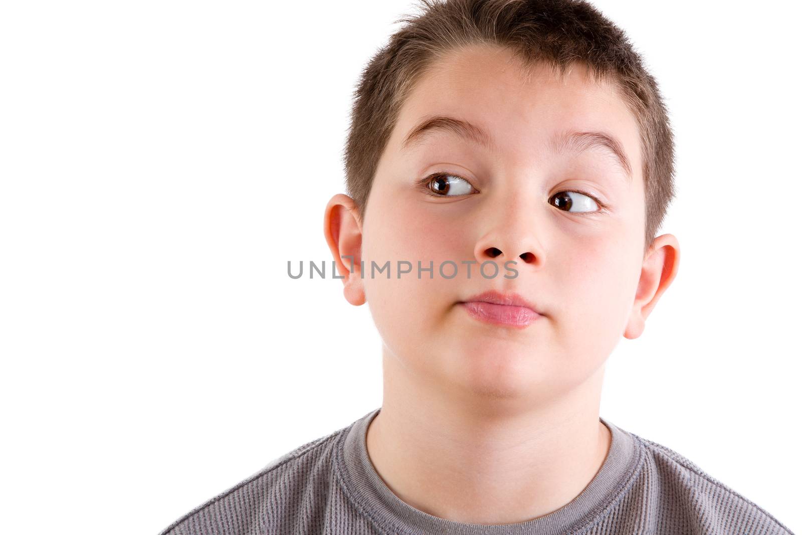 Head and Shoulders Close Up Portrait of Young Boy Looking to the Side with Curious Expression in front of White Background with Copy Space
