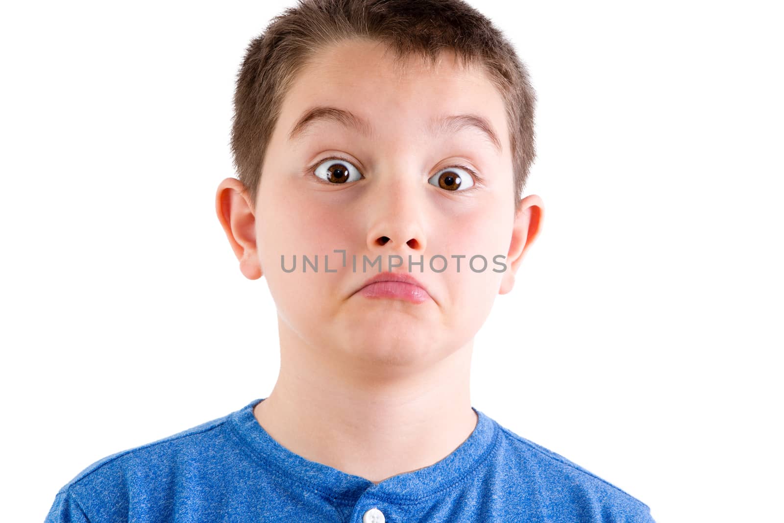 Head and Shoulders Close Up Portrait of Young Boy Wearing Blue Shirt Looking at Camera with Surprised Expression and Down Turned Mouth in Studio with White Background