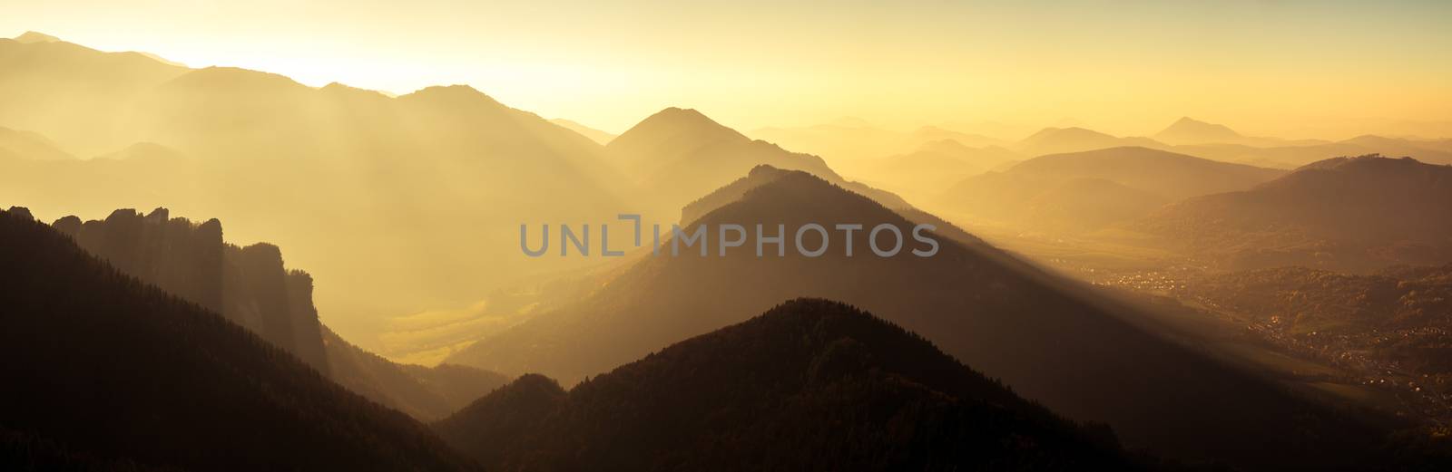 Panoramic scenic view of mountains and hills silhouette at sunse by martinm303