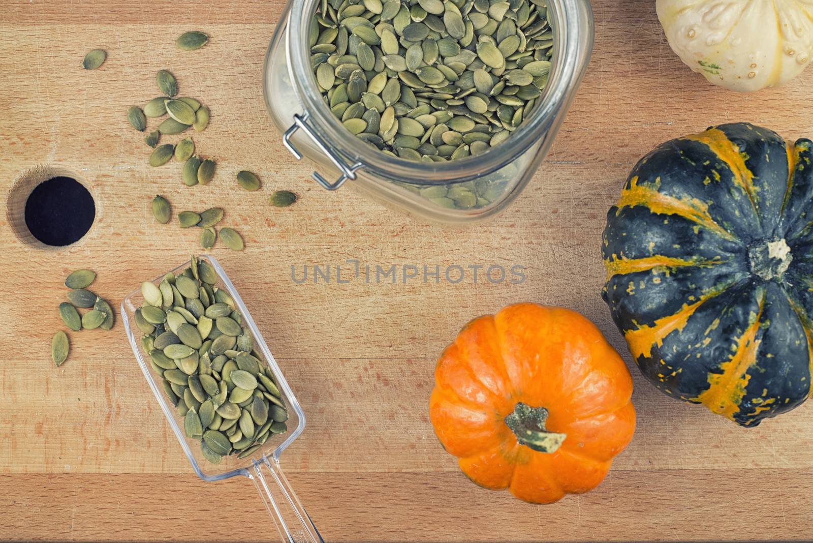Colorful background with pumpkin seeds and squash over wooden background