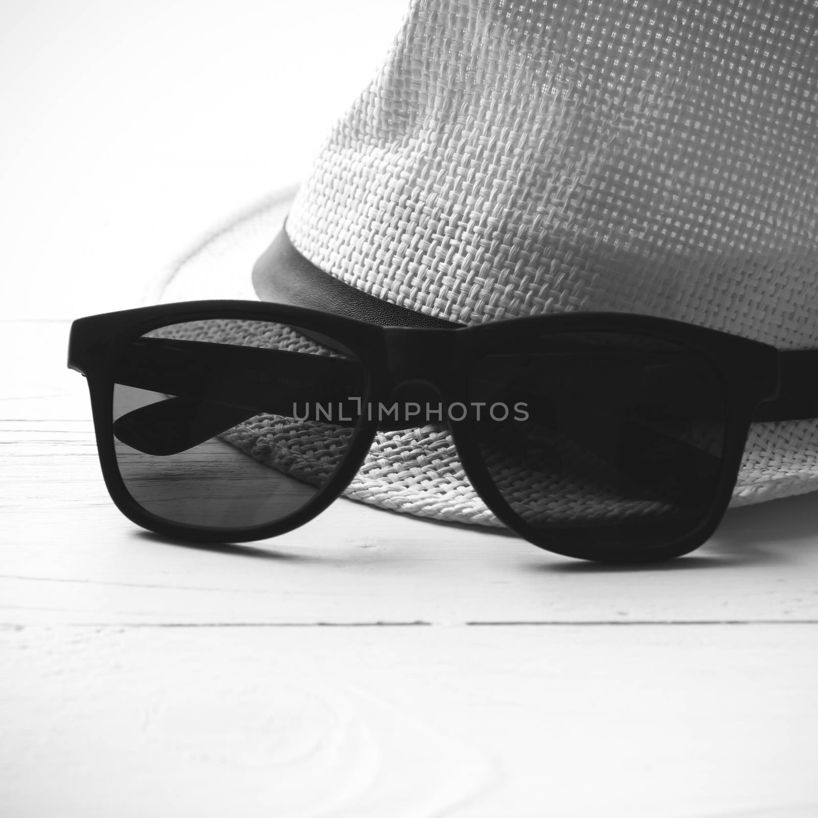 hat and sunglasses on white table black and white color