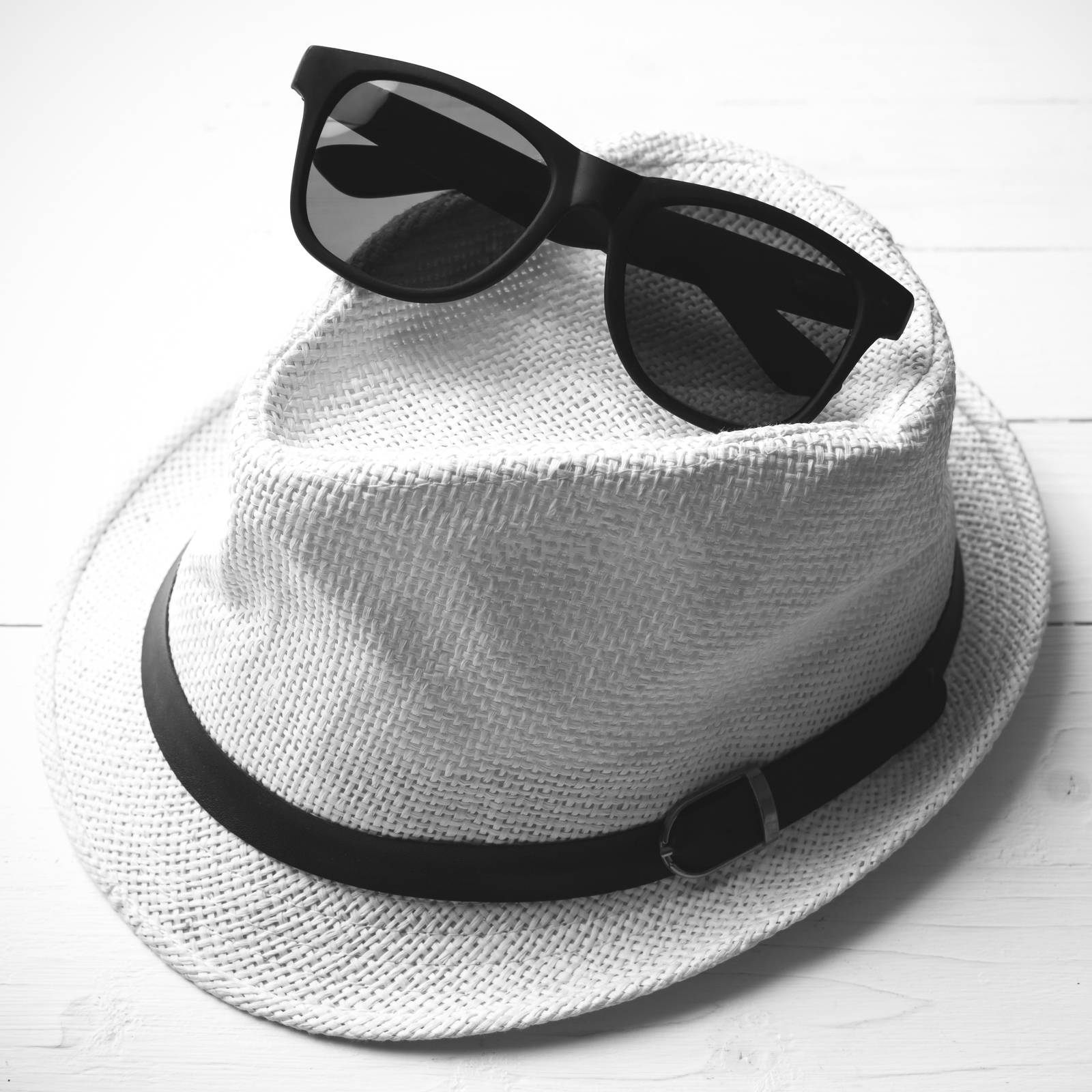 hat and sunglasses on white table black and white color